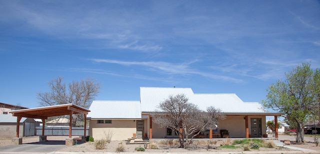 view of front of home with stucco siding, fence, and metal roof