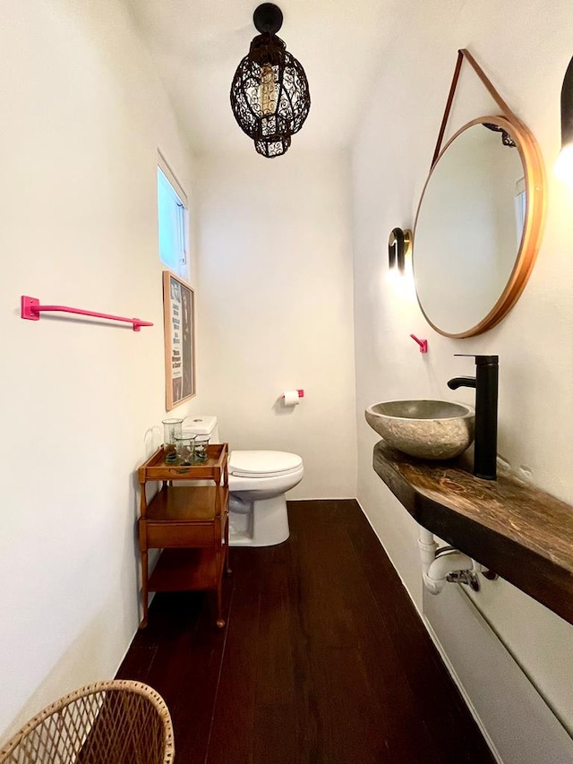 half bathroom featuring a sink, toilet, and wood finished floors