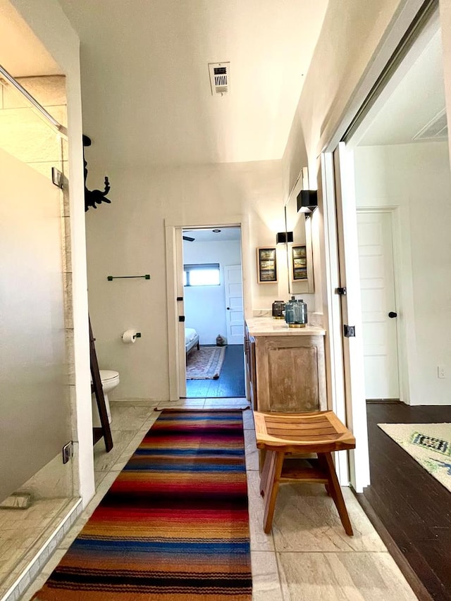 ensuite bathroom featuring connected bathroom, vanity, a shower stall, and toilet