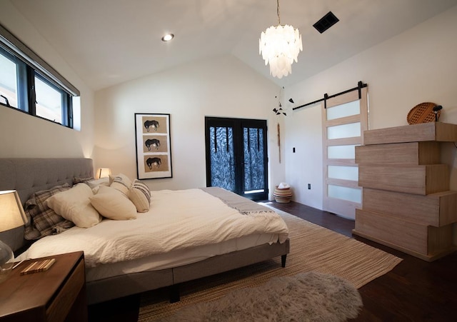 bedroom with a barn door, lofted ceiling, wood finished floors, and a chandelier