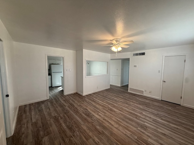 unfurnished bedroom with baseboards, visible vents, dark wood-style flooring, and freestanding refrigerator