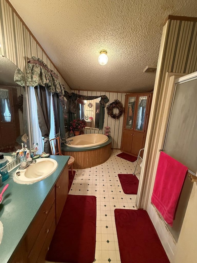 bathroom with vanity, a textured ceiling, and plus walk in shower