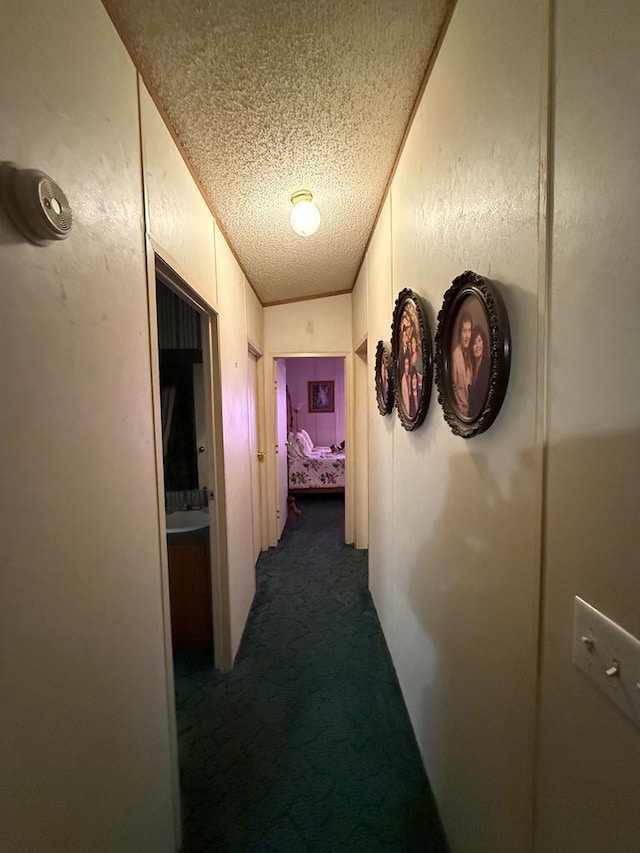 corridor featuring dark carpet and a textured ceiling