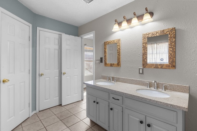 bathroom featuring tile patterned flooring, a textured ceiling, a sink, and a textured wall