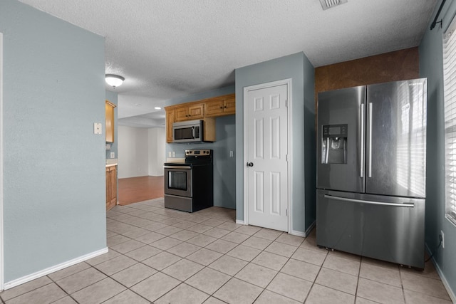 kitchen featuring light tile patterned floors, plenty of natural light, appliances with stainless steel finishes, and a textured ceiling