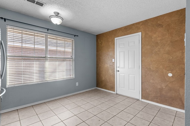 unfurnished room with visible vents, a textured ceiling, baseboards, and light tile patterned floors