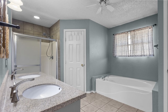 bathroom with tile patterned flooring, a sink, a textured ceiling, and a bath