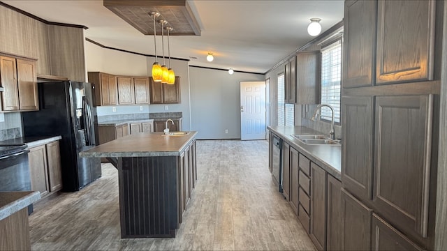 kitchen with pendant lighting, sink, crown molding, light hardwood / wood-style flooring, and an island with sink