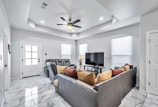 living area featuring marble finish floor, baseboards, visible vents, and a raised ceiling