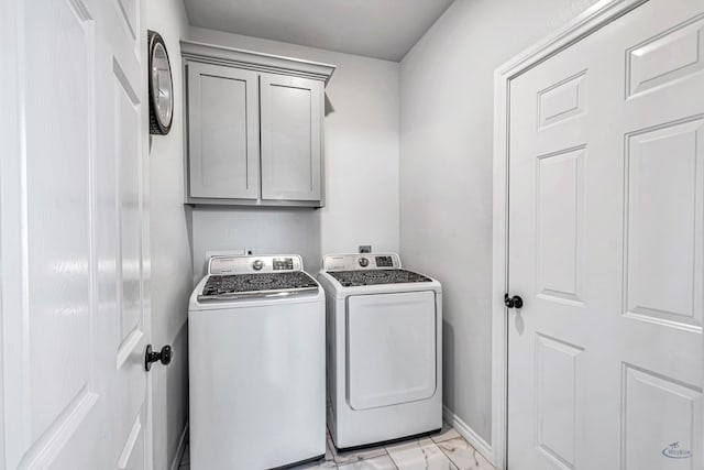 washroom with washing machine and dryer, marble finish floor, cabinet space, and baseboards