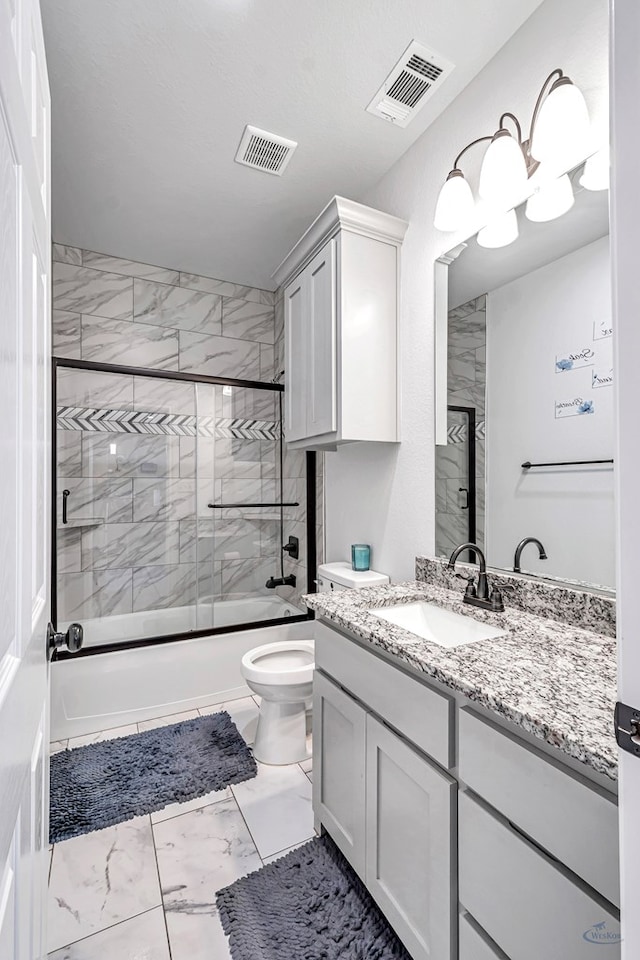 bathroom featuring marble finish floor, shower / bath combination with glass door, visible vents, and vanity