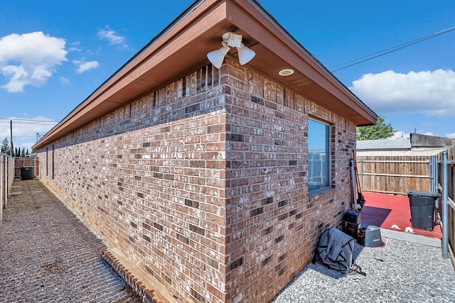 view of side of home with fence and brick siding