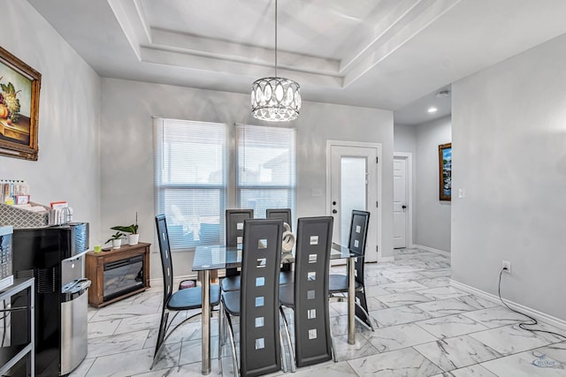 dining space featuring a chandelier, marble finish floor, a raised ceiling, and baseboards