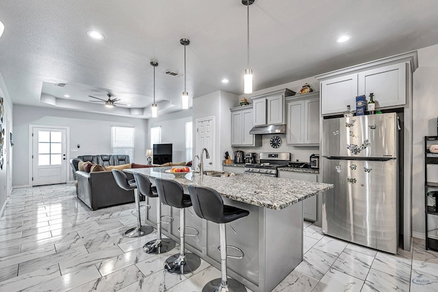 kitchen with appliances with stainless steel finishes, marble finish floor, a kitchen island with sink, and gray cabinetry