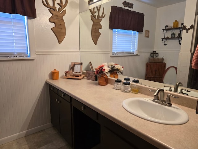 bathroom featuring vanity, a wainscoted wall, and tile patterned flooring