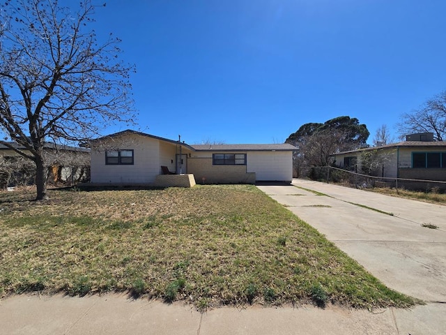 view of front facade with an attached garage, concrete driveway, a front yard, and fence