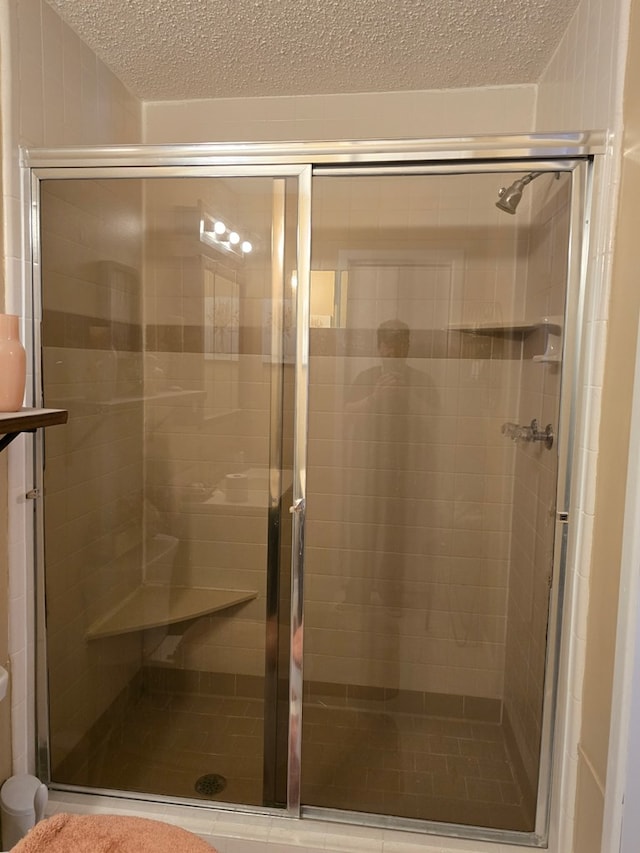 full bath featuring a stall shower and a textured ceiling