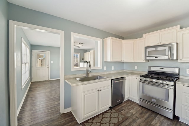 kitchen with dark hardwood / wood-style flooring, stainless steel appliances, white cabinetry, and sink