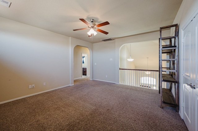 spare room with ceiling fan, visible vents, arched walkways, and carpet flooring