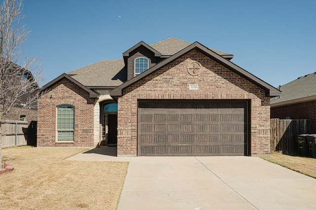 view of front facade featuring a garage, fence, and brick siding