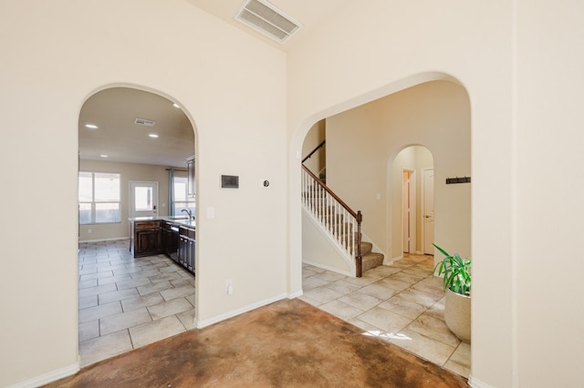 foyer with stairs, visible vents, and arched walkways