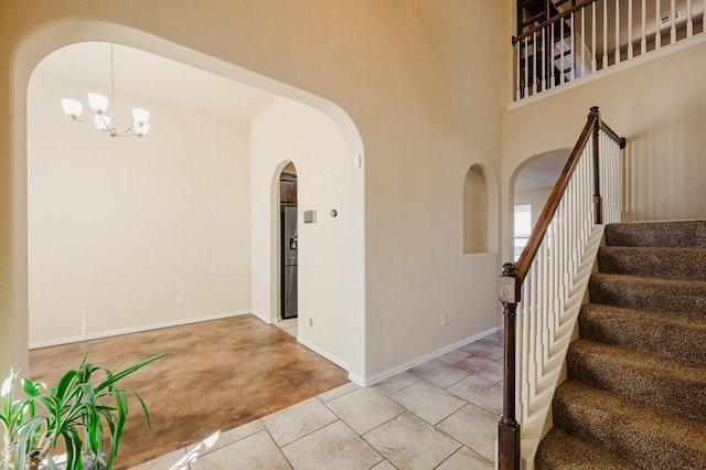 foyer featuring light tile patterned floors, a high ceiling, an inviting chandelier, baseboards, and stairs