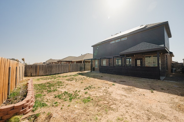 rear view of property with a fenced backyard and brick siding