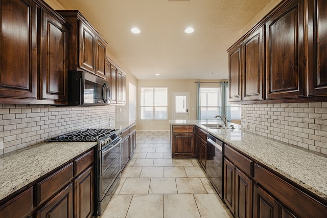 kitchen with tasteful backsplash, appliances with stainless steel finishes, light stone counters, and a sink