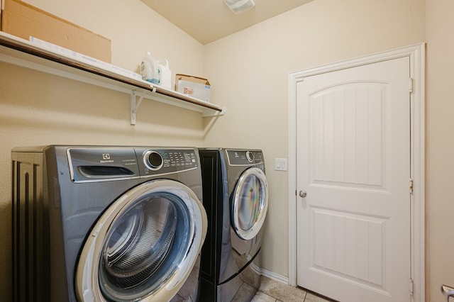 clothes washing area with light tile patterned floors, laundry area, washer and clothes dryer, and baseboards