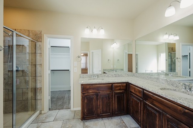 bathroom with double vanity, a shower stall, a walk in closet, and a sink