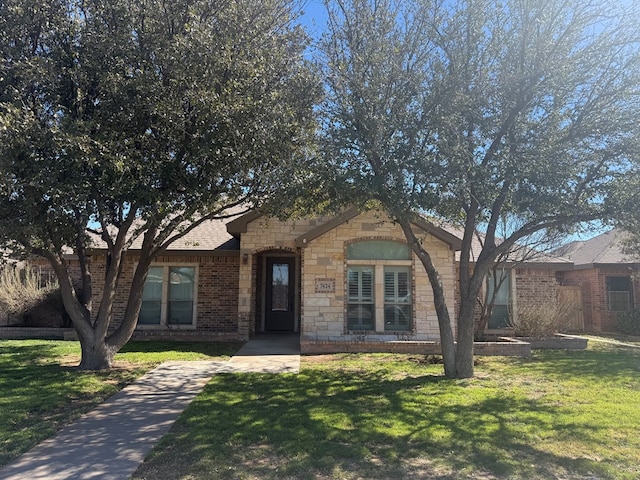 ranch-style house featuring stone siding, brick siding, and a front yard