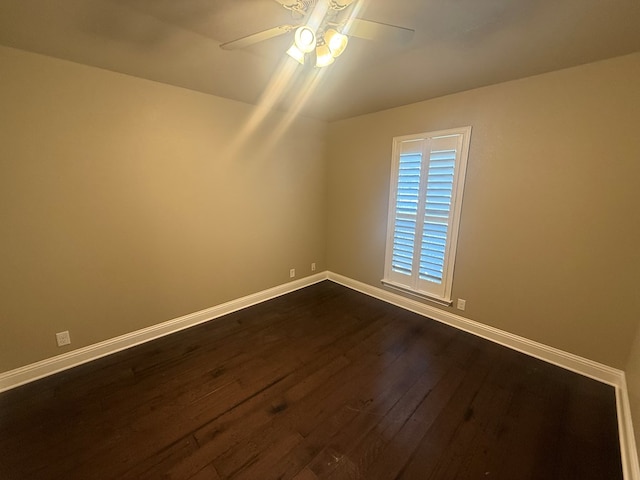 empty room with a ceiling fan, baseboards, and dark wood-style flooring