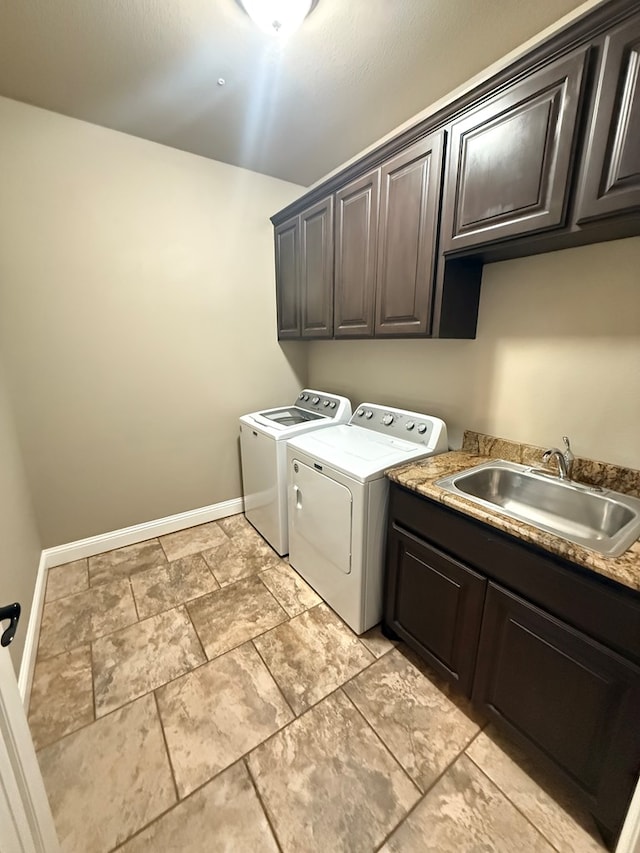 laundry area with cabinet space, baseboards, separate washer and dryer, and a sink