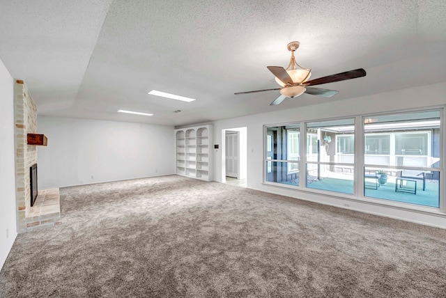 unfurnished living room featuring ceiling fan, a brick fireplace, carpet flooring, and a textured ceiling