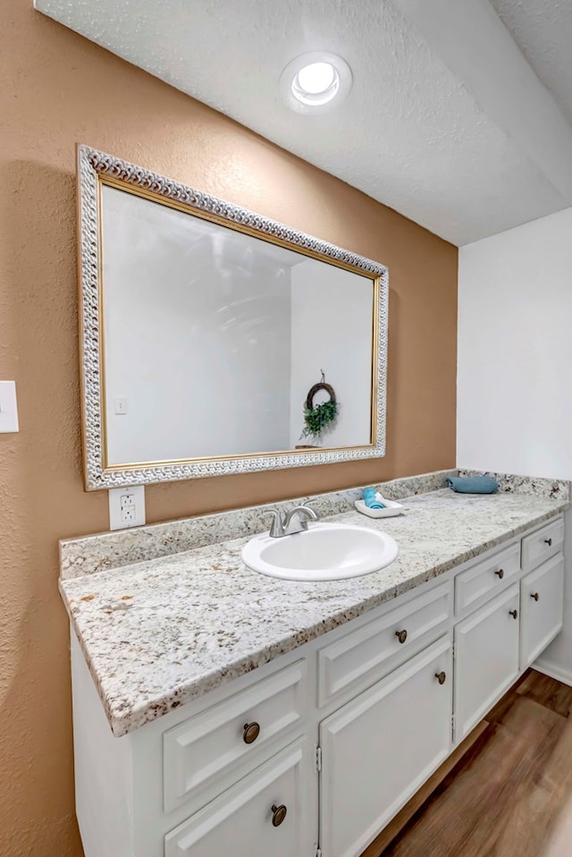 bathroom featuring hardwood / wood-style flooring, vanity, and a textured ceiling