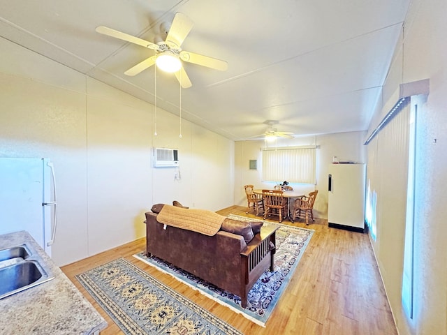 living room with light hardwood / wood-style floors, an AC wall unit, ceiling fan, and sink