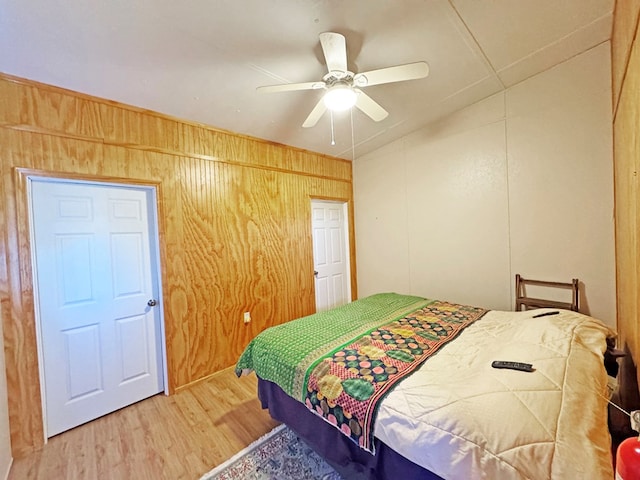 bedroom featuring hardwood / wood-style floors, ceiling fan, lofted ceiling, and wood walls