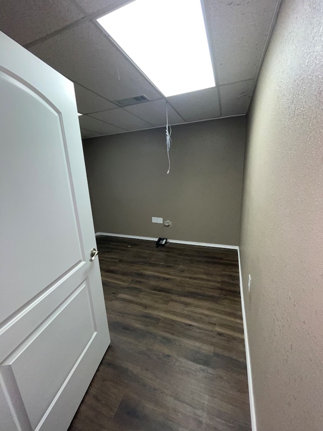 basement with a drop ceiling and dark hardwood / wood-style flooring