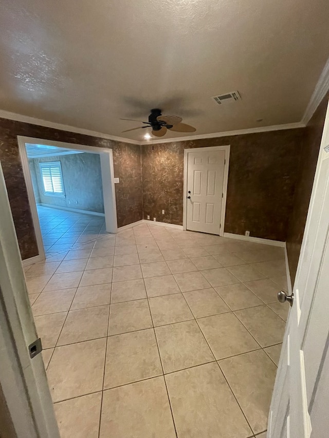 spare room featuring ceiling fan, light tile patterned flooring, ornamental molding, and a textured ceiling