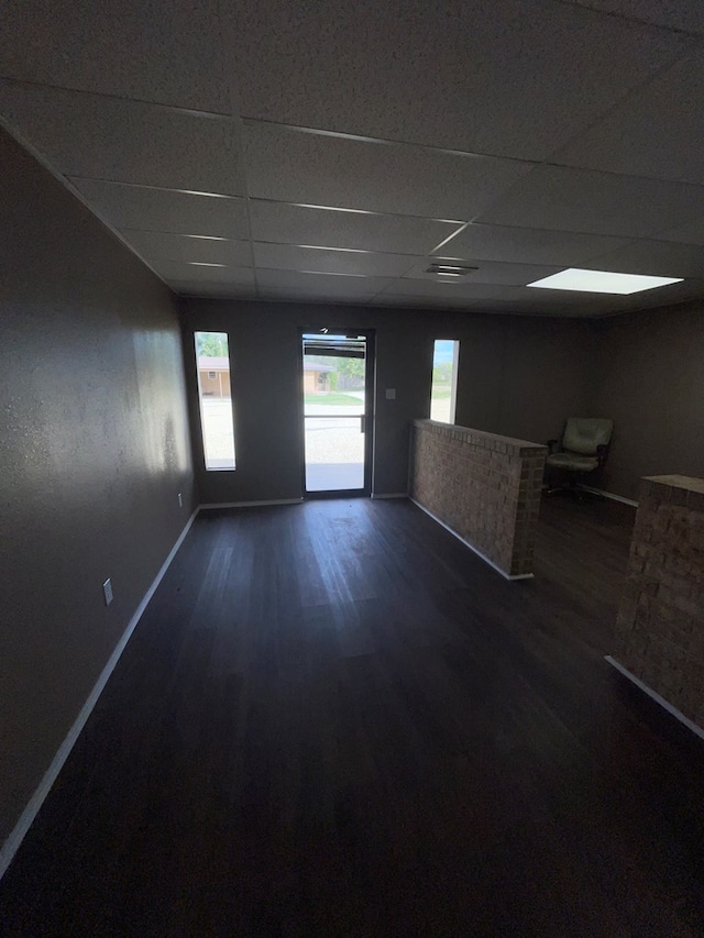 spare room featuring dark hardwood / wood-style flooring and a drop ceiling