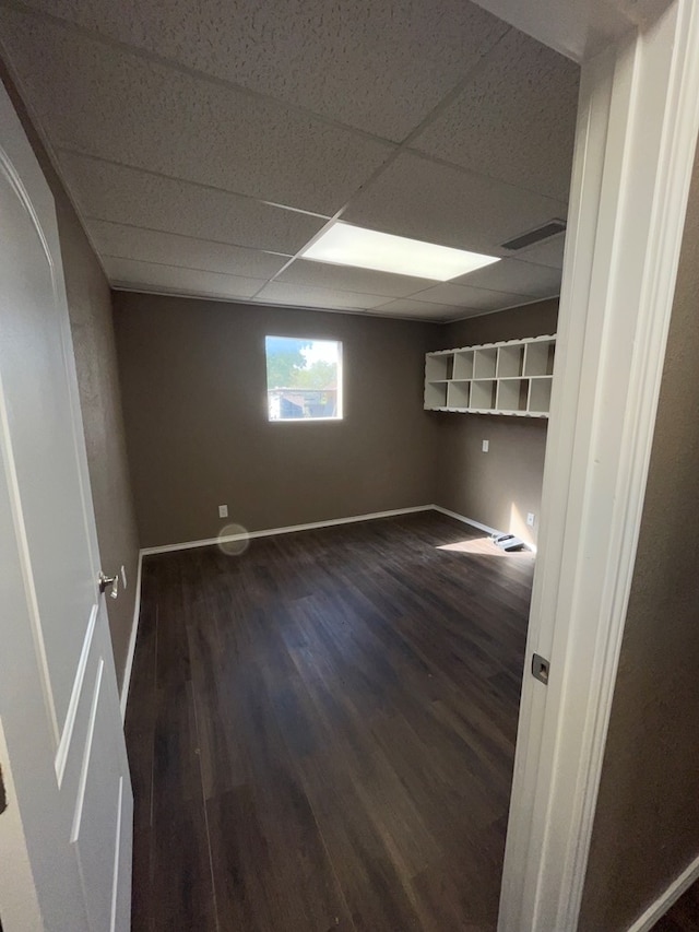 unfurnished room featuring a drop ceiling and dark wood-type flooring