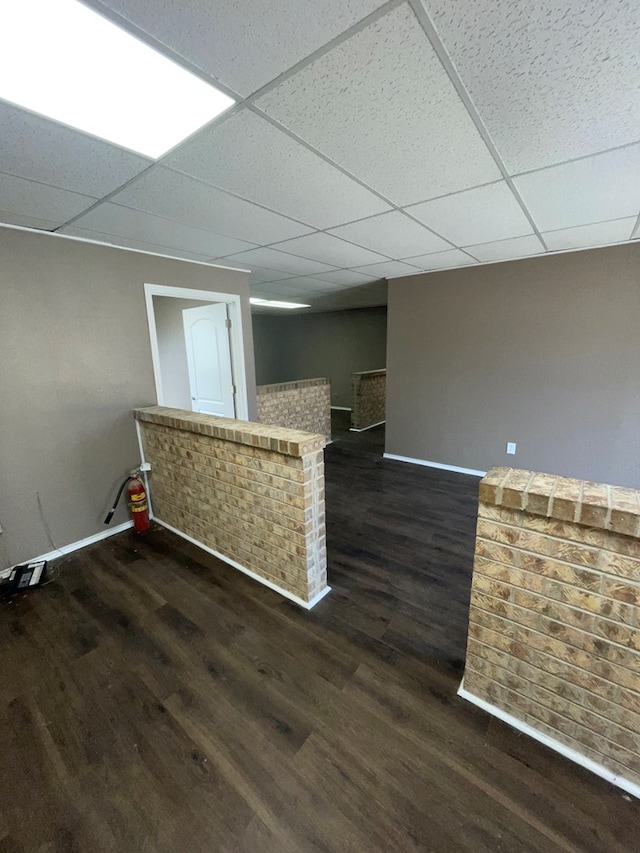 interior space featuring a paneled ceiling and dark wood-type flooring