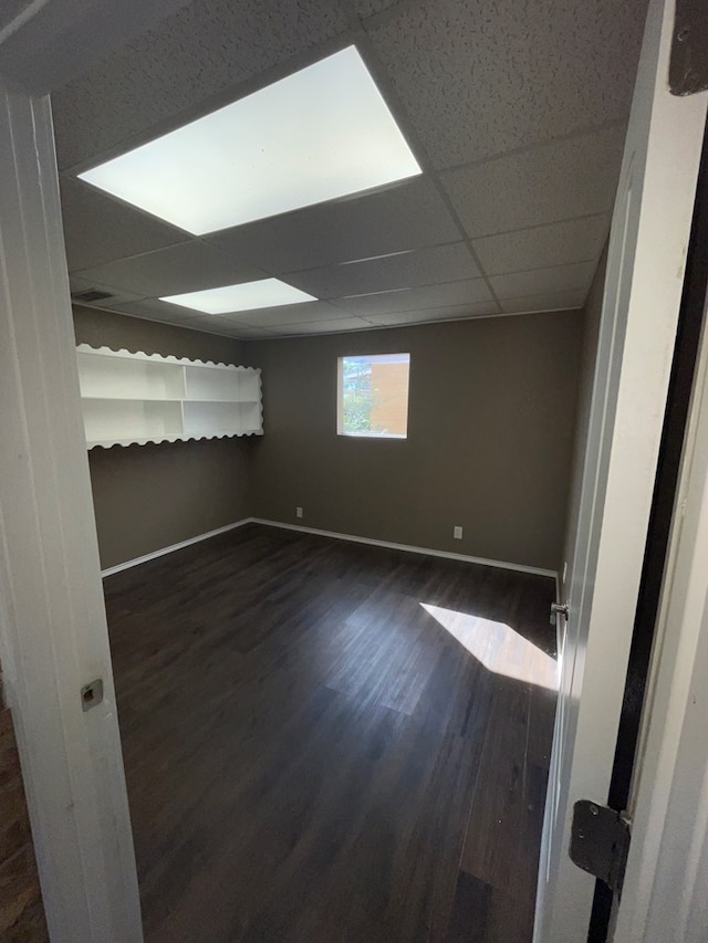 empty room featuring dark hardwood / wood-style floors and a drop ceiling