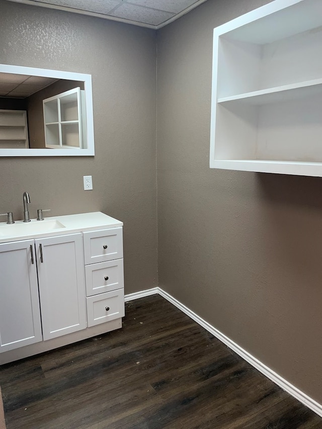 bathroom with a drop ceiling, vanity, and hardwood / wood-style flooring