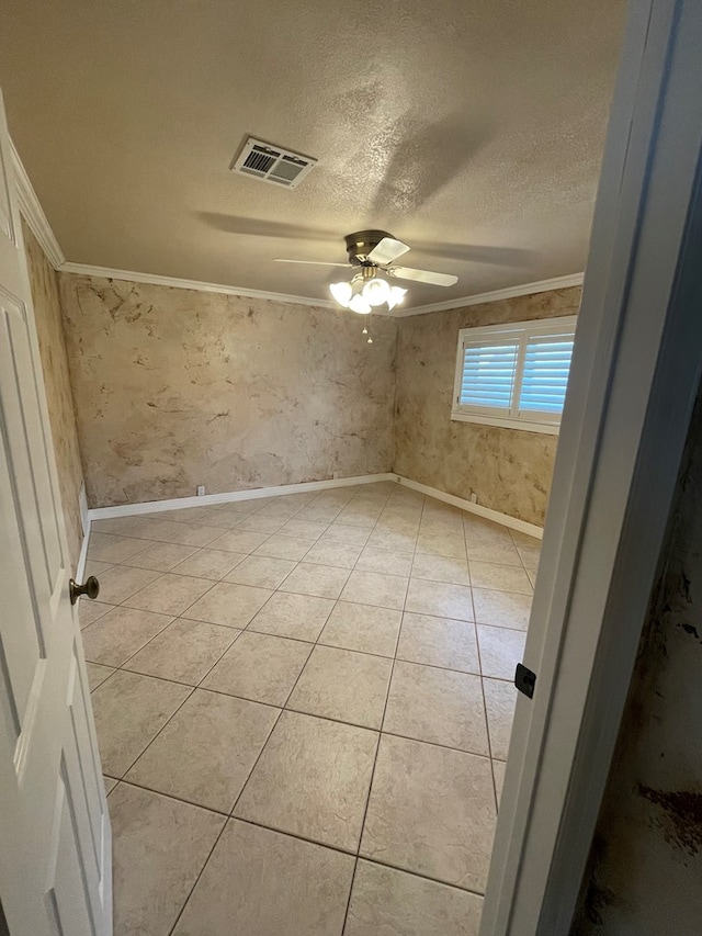 empty room featuring ceiling fan, light tile patterned flooring, ornamental molding, and a textured ceiling