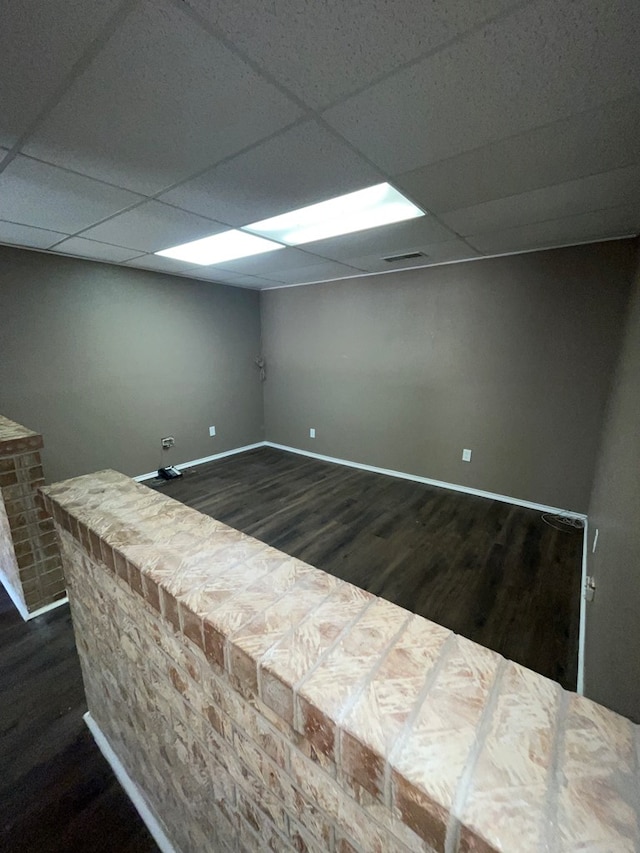 interior space featuring dark hardwood / wood-style flooring and a drop ceiling