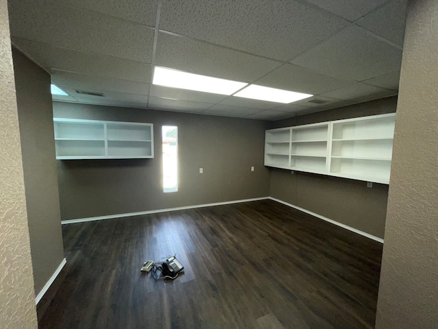 unfurnished room featuring a drop ceiling and dark wood-type flooring