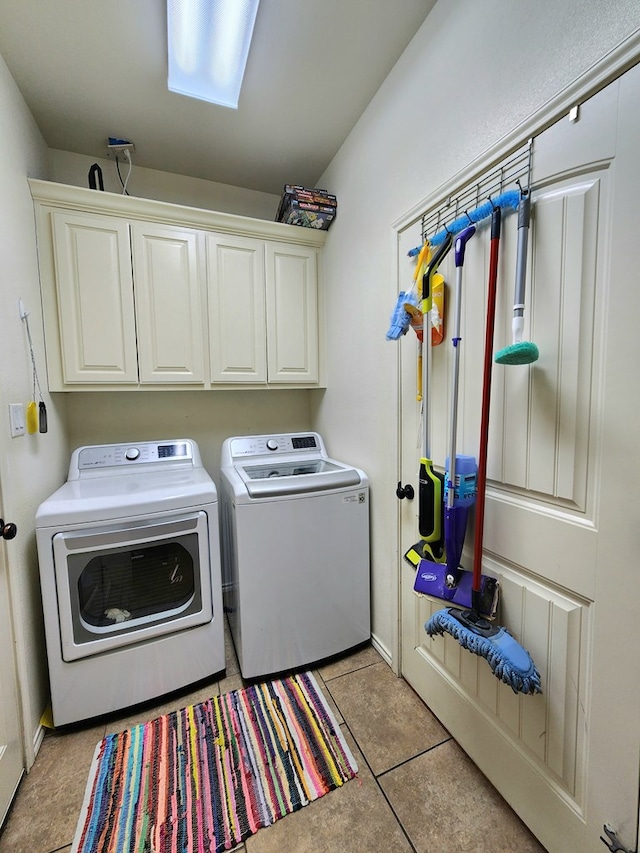 clothes washing area with cabinets, light tile patterned floors, and washing machine and clothes dryer