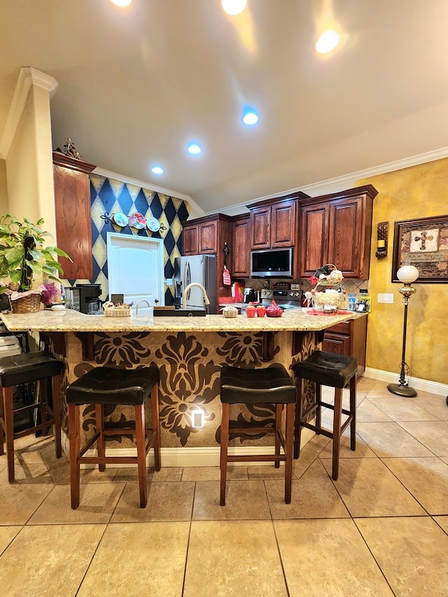 kitchen featuring crown molding, a breakfast bar area, appliances with stainless steel finishes, light tile patterned flooring, and kitchen peninsula