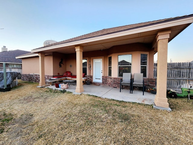 back of property with a patio, a yard, and an outdoor fire pit